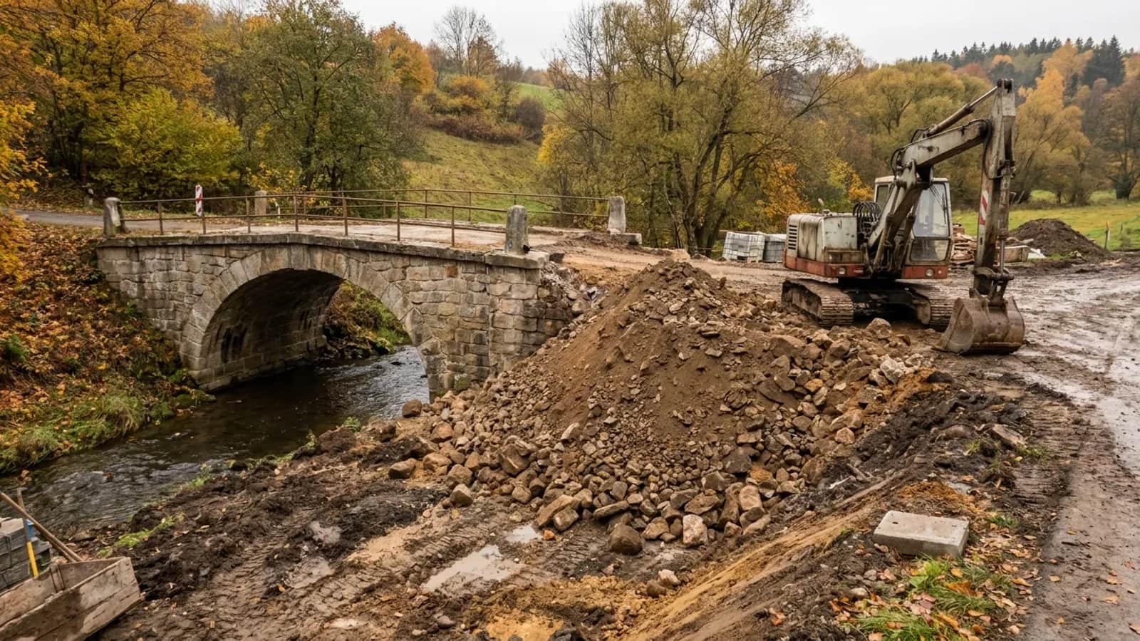 Starý kamenný klenbový most přes říčku při rekonstrukci silnice, vedle bagr.